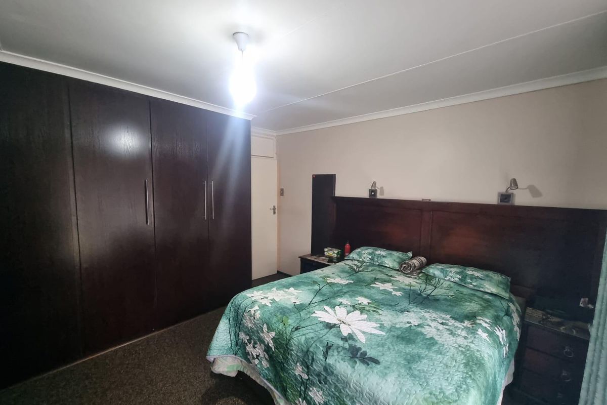 A bedroom featuring built-in dark wood wardrobes and a matching integrated headboard with wall-mounted reading lights.