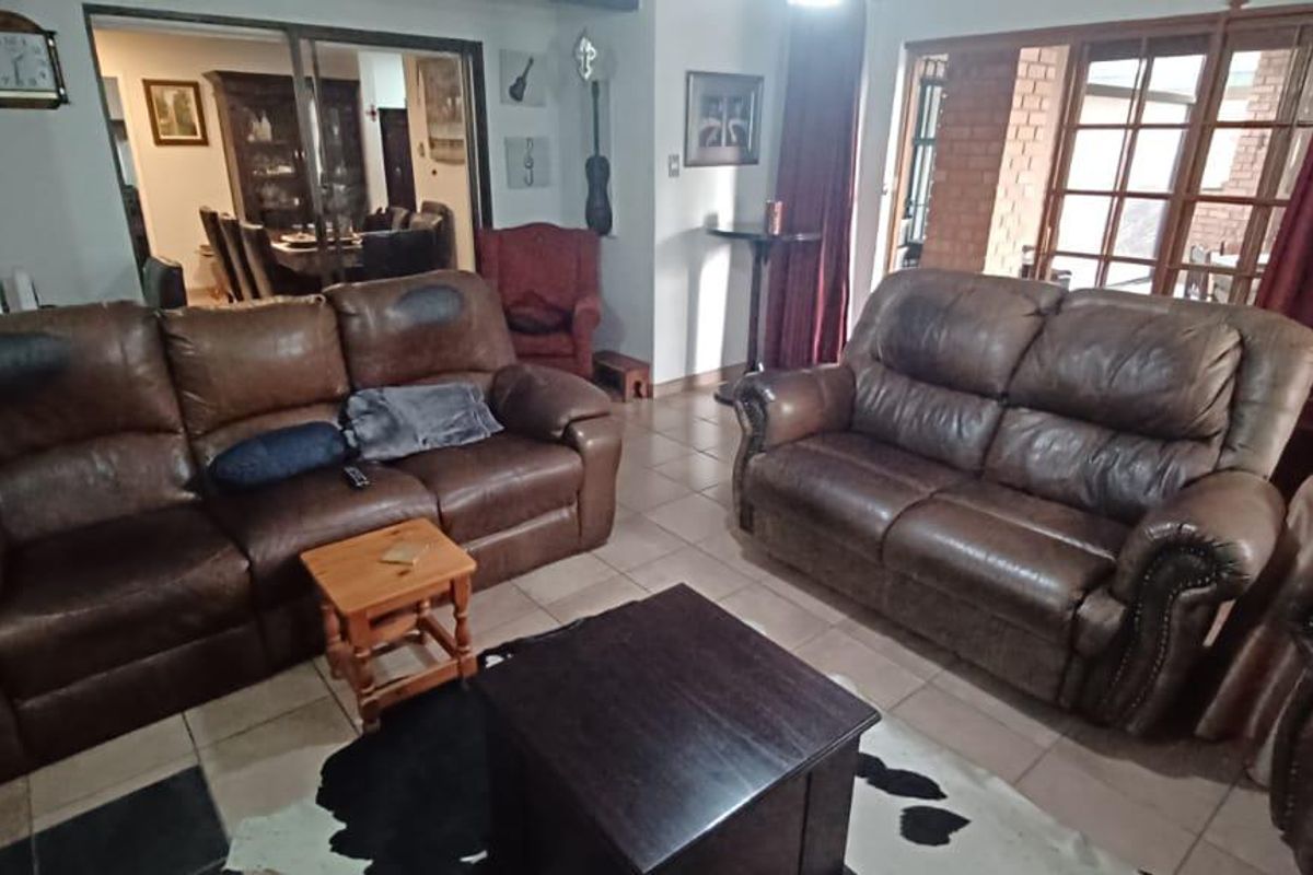 A spacious living room featuring tiled flooring and large sliding glass doors that provide access to an outdoor patio area.