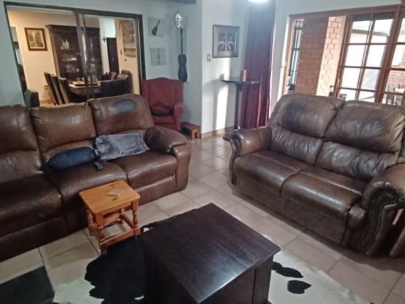 A spacious living room featuring tiled flooring and large sliding glass doors that provide access to an outdoor patio area.