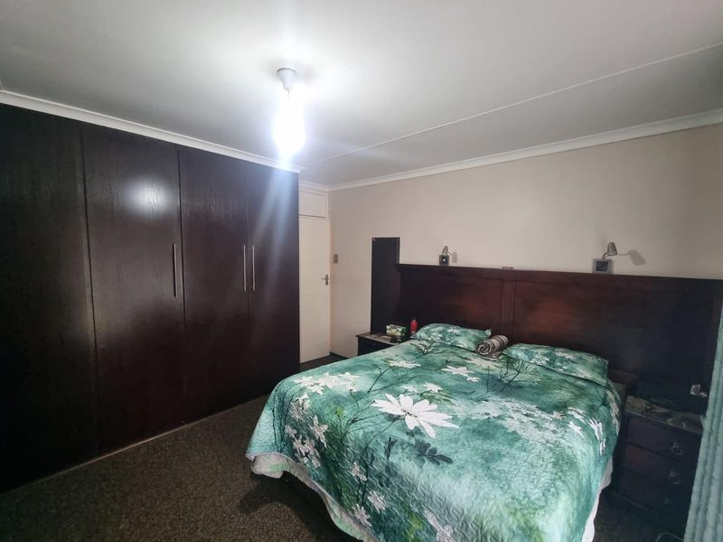 A bedroom featuring built-in dark wood wardrobes and a matching integrated headboard with wall-mounted reading lights.