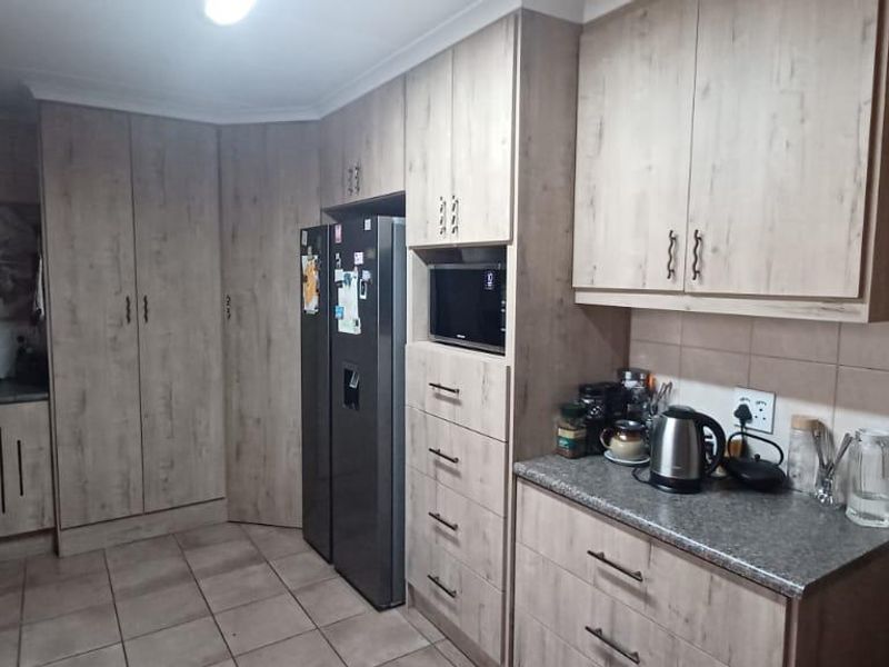 A functional kitchen featuring wood-look cabinetry, stone-style countertops, tiled flooring, and integrated storage space with a built-in microwave.