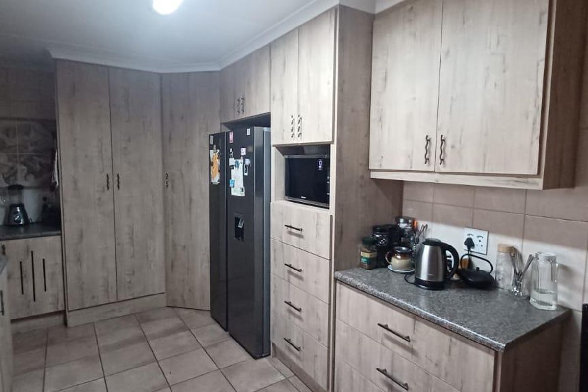 A functional kitchen featuring wood-look cabinetry, stone-style countertops, tiled flooring, and integrated storage space with a built-in microwave.