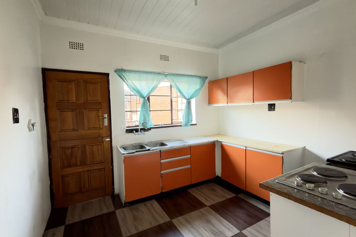 A functional kitchen featuring original cabinetry, a double sink, and a built-in hob, offering potential for a modern renovation.