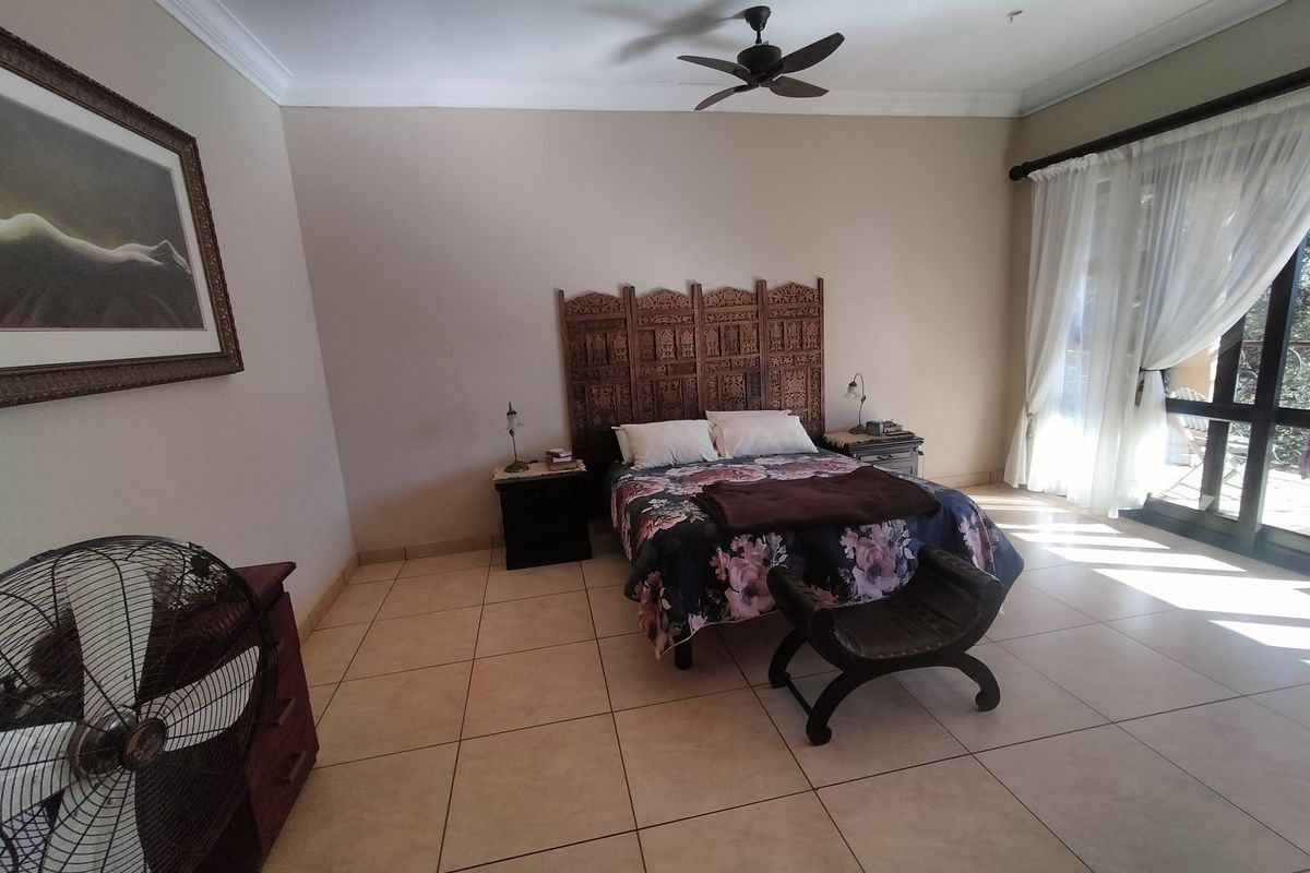 Spacious bedroom featuring large format floor tiles, a ceiling fan, and sliding glass doors providing natural light and access to the outdoors.