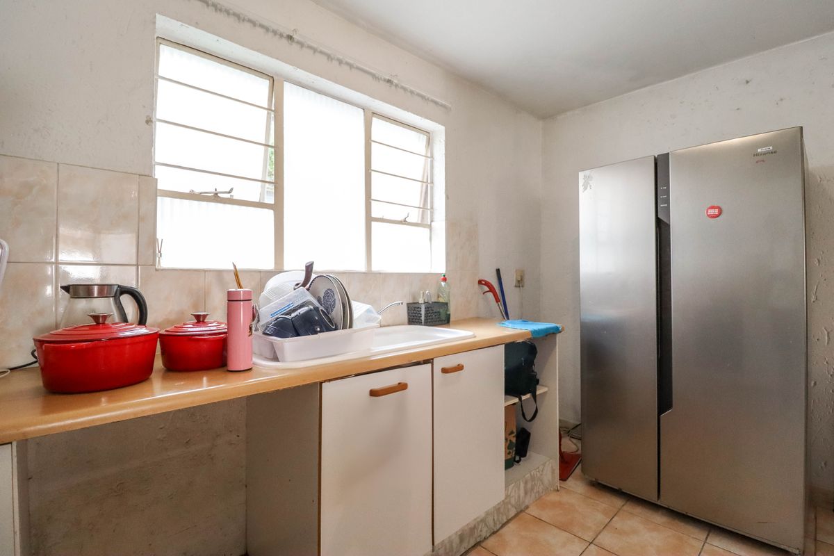 A functional kitchen area featuring built-in cabinetry, a single basin sink, and tiled splashbacks, offering potential for modernization and renovation.