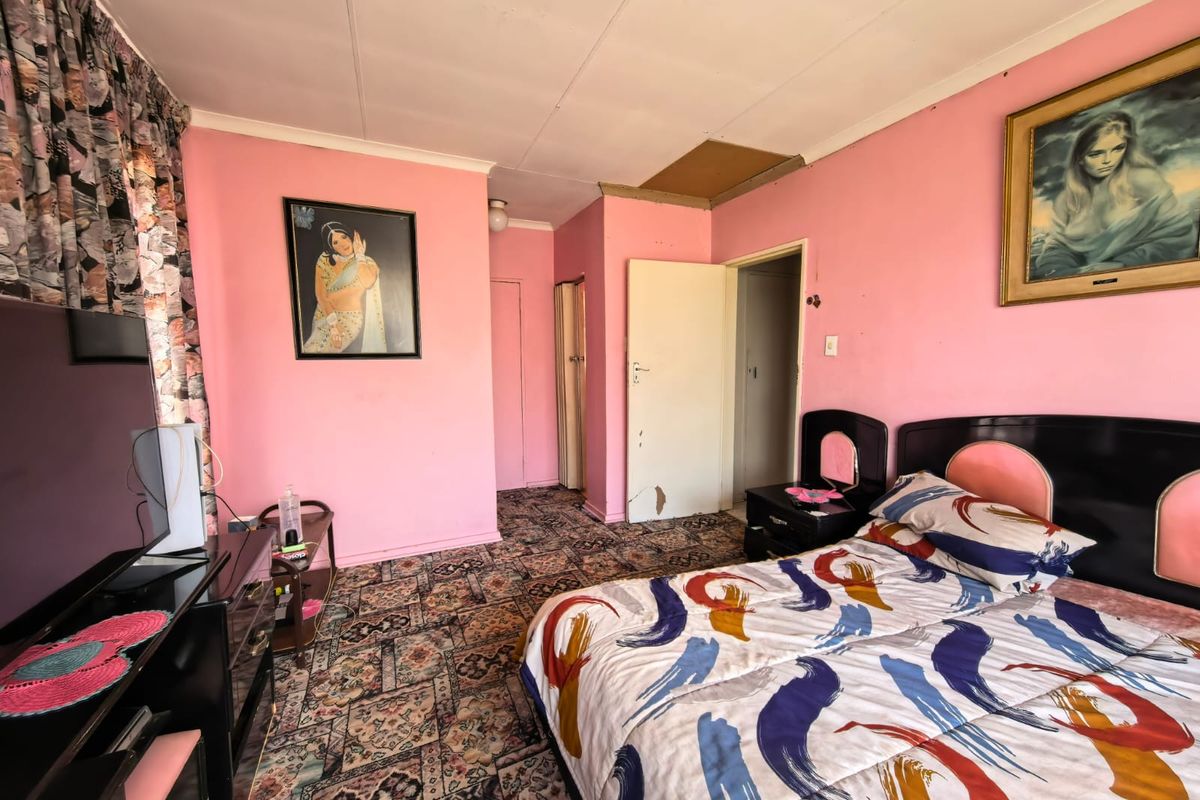 A bedroom featuring pink walls, carpeted flooring, and built-in cupboard storage, requiring cosmetic updates to modernize the space.
