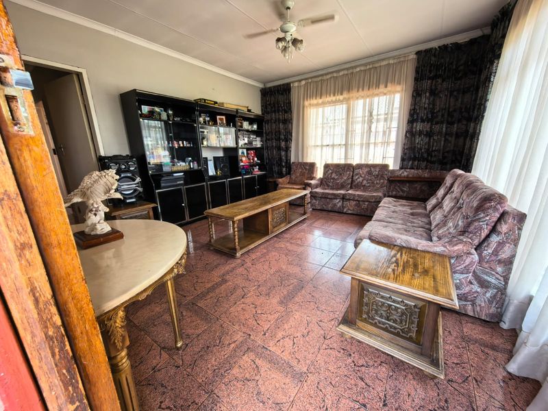 A spacious living room featuring tiled flooring, a ceiling fan, and a large built-in display cabinet, offering a functional layout for family relaxation.
