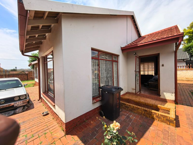Front exterior view of the house featuring brick paving, tiled roofing, and a small entrance porch with brick steps.