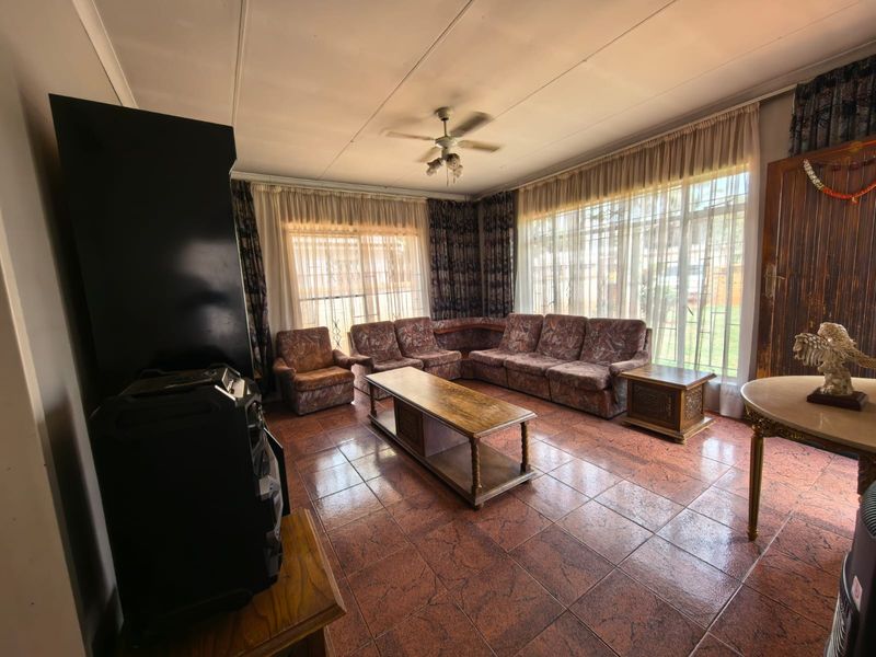 Spacious living room featuring large windows, tiled flooring, and a ceiling fan, offering a bright and functional space for relaxation.