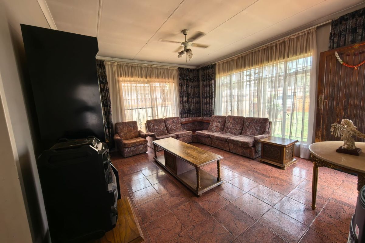 Spacious living room featuring large windows, tiled flooring, and a ceiling fan, offering a bright and functional space for relaxation.