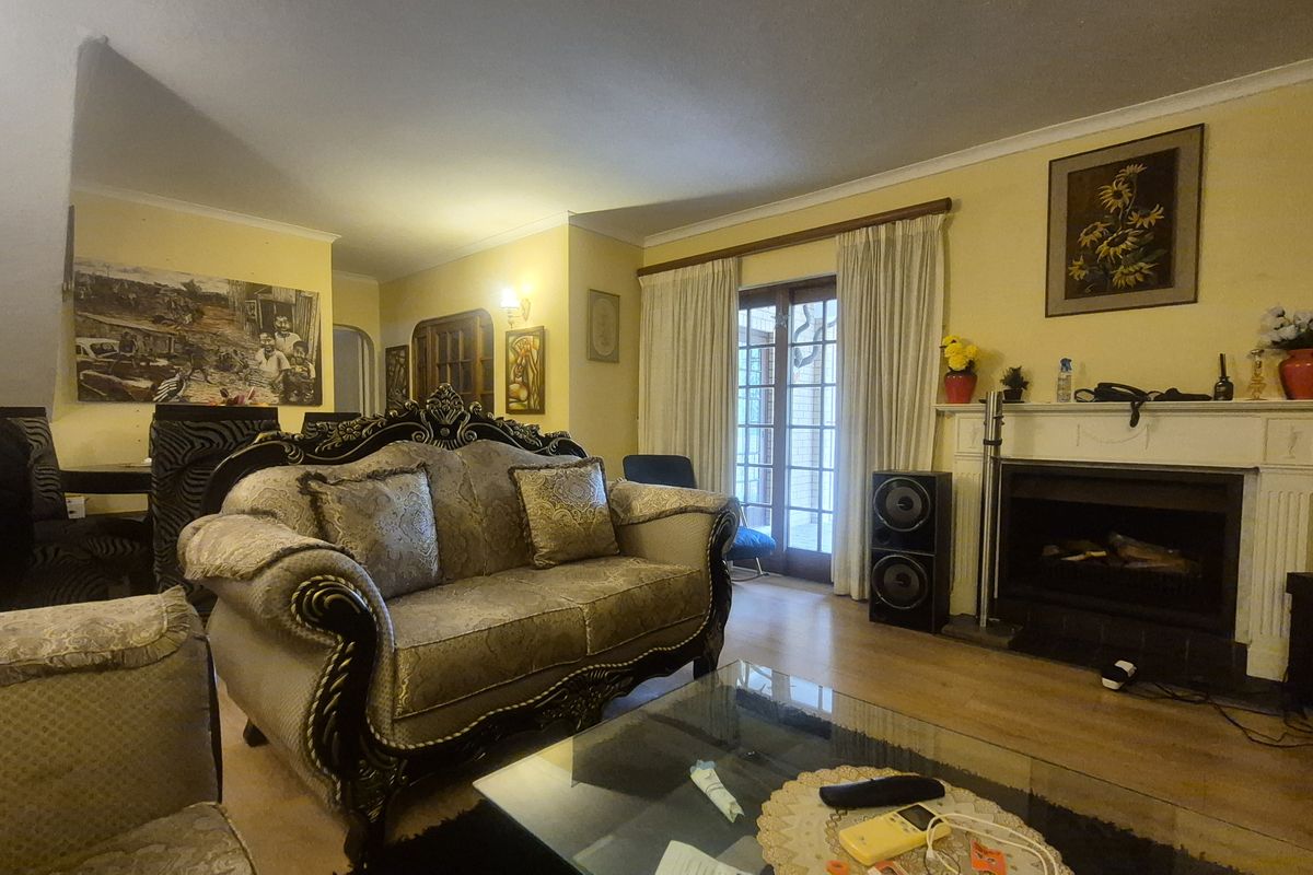 A spacious living room featuring laminate flooring, a traditional fireplace with a mantel, and French doors providing access to the outdoor area.