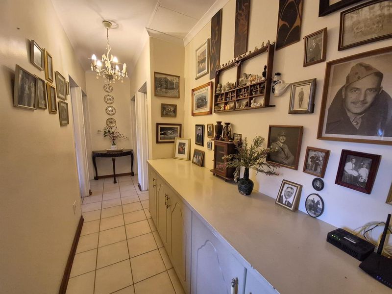 A well-lit hallway featuring extensive built-in cabinetry for storage, tiled flooring, and decorative ceiling cornice.