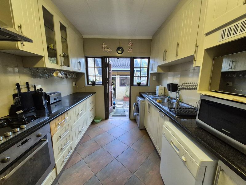 Functional galley-style kitchen featuring ample built-in cabinetry, granite countertops, integrated appliances, and direct access to the rear exterior area.