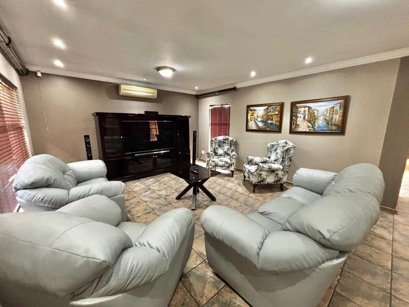 A spacious living room featuring tiled flooring, recessed downlighting, and a wall-mounted split-system air conditioner.