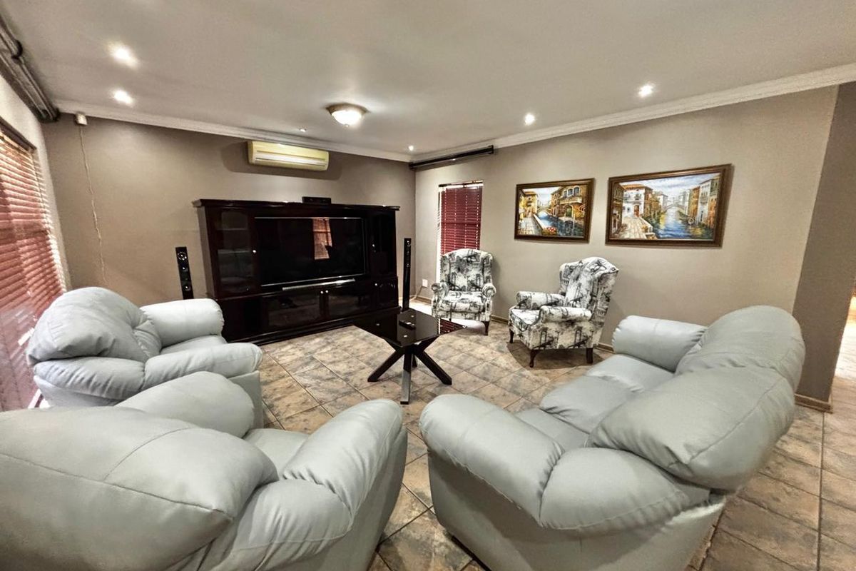 A spacious living room featuring tiled flooring, recessed downlighting, and a wall-mounted split-system air conditioner.