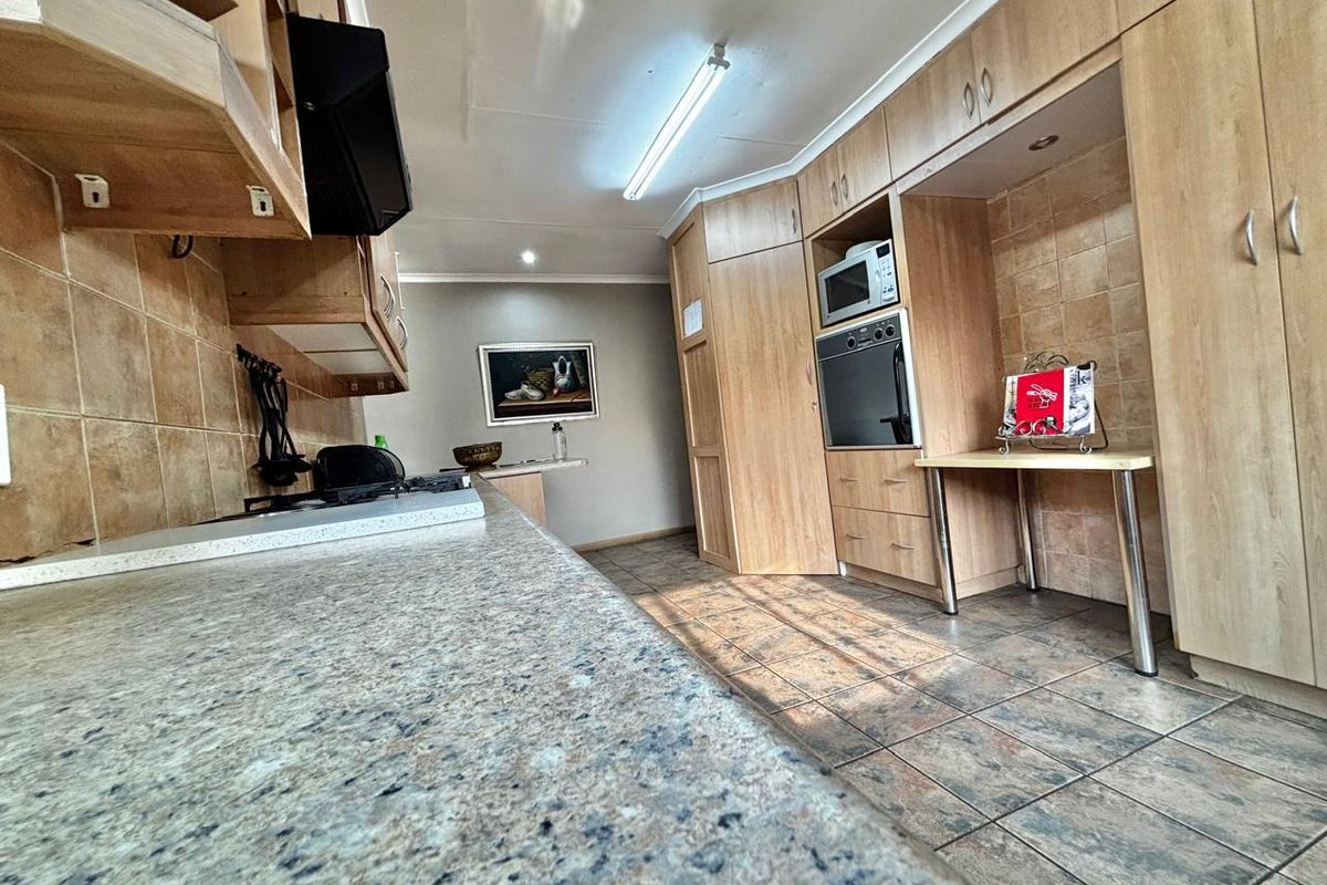 A functional kitchen featuring light wood cabinetry, granite countertops, tiled backsplash, and integrated appliances including an oven and microwave.