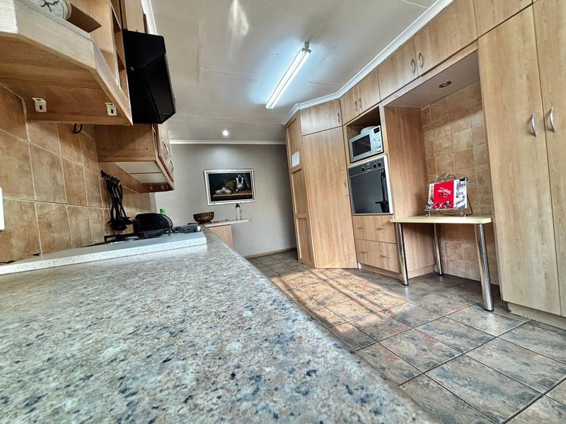 A functional kitchen featuring light wood cabinetry, granite countertops, tiled backsplash, and integrated appliances including an oven and microwave.