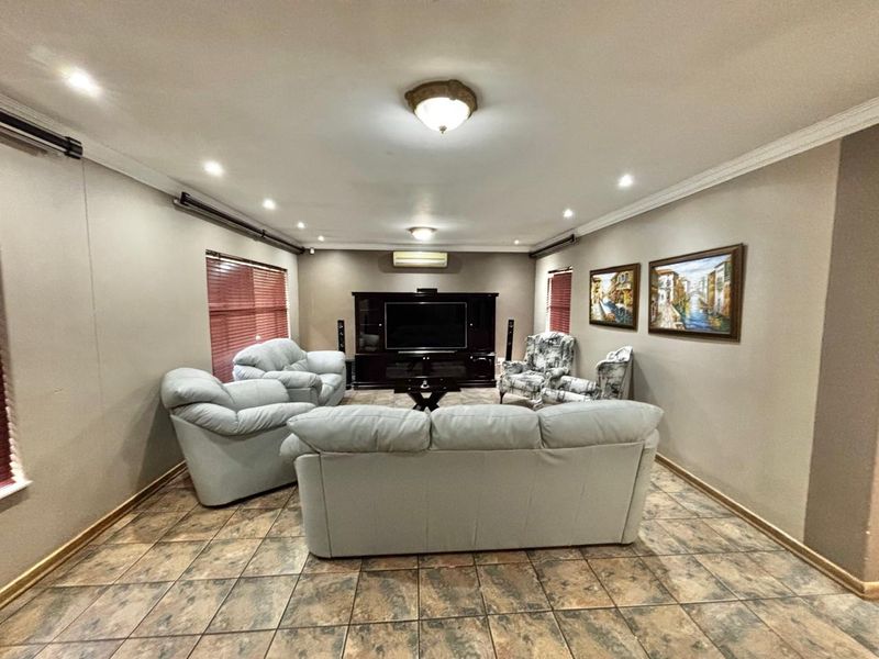 Spacious living room featuring tiled flooring, recessed downlighting, crown molding, and a wall-mounted split system air conditioner.
