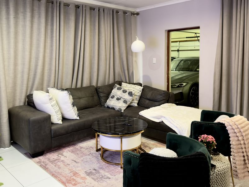 A comfortable living room featuring tiled flooring and direct access to the garage area.