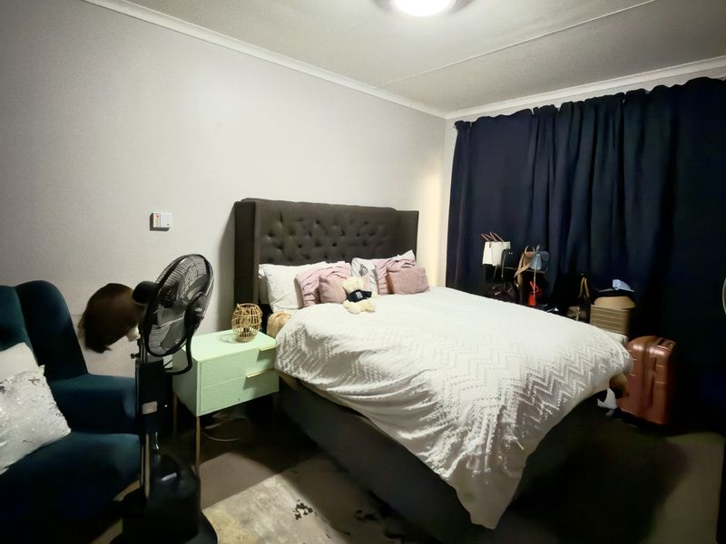 A functional bedroom featuring neutral wall finishes, a built-in wardrobe, and a ceiling light fixture, providing a comfortable and private sleeping space.