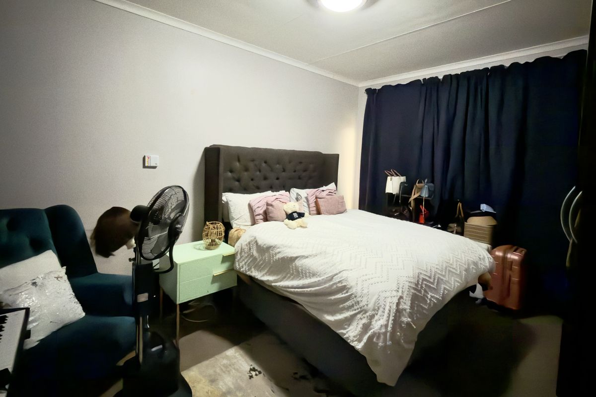 A functional bedroom featuring neutral wall finishes, a built-in wardrobe, and a ceiling light fixture, providing a comfortable and private sleeping space.