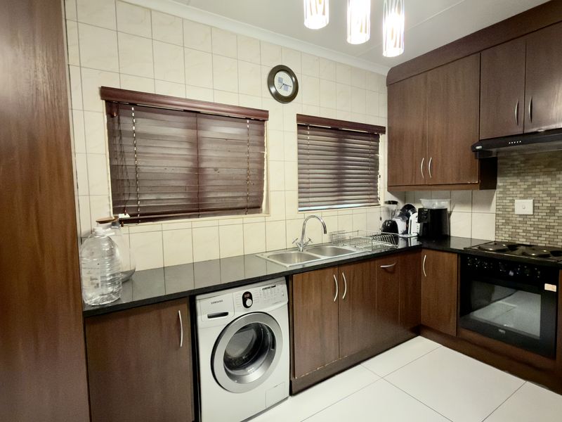 A functional kitchen featuring dark wood cabinetry, granite countertops, a built-in oven with hob, and a tiled backsplash.