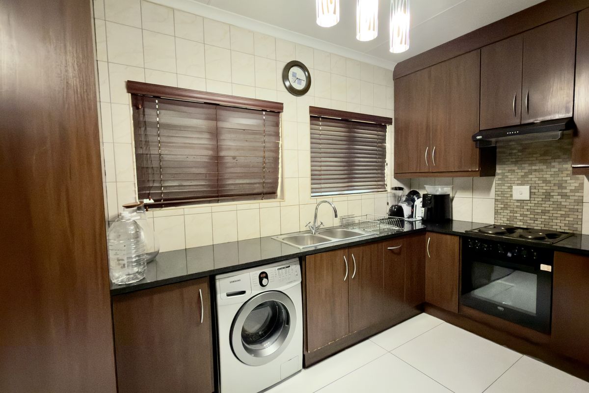 A functional kitchen featuring dark wood cabinetry, granite countertops, a built-in oven with hob, and a tiled backsplash.