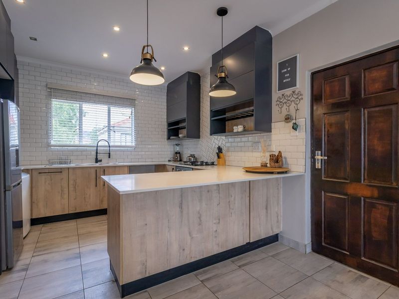 Modern kitchen featuring wood-look cabinetry, white quartz countertops, subway tile backsplash, and high-quality fixtures, offering a clean and functional culinary space.
