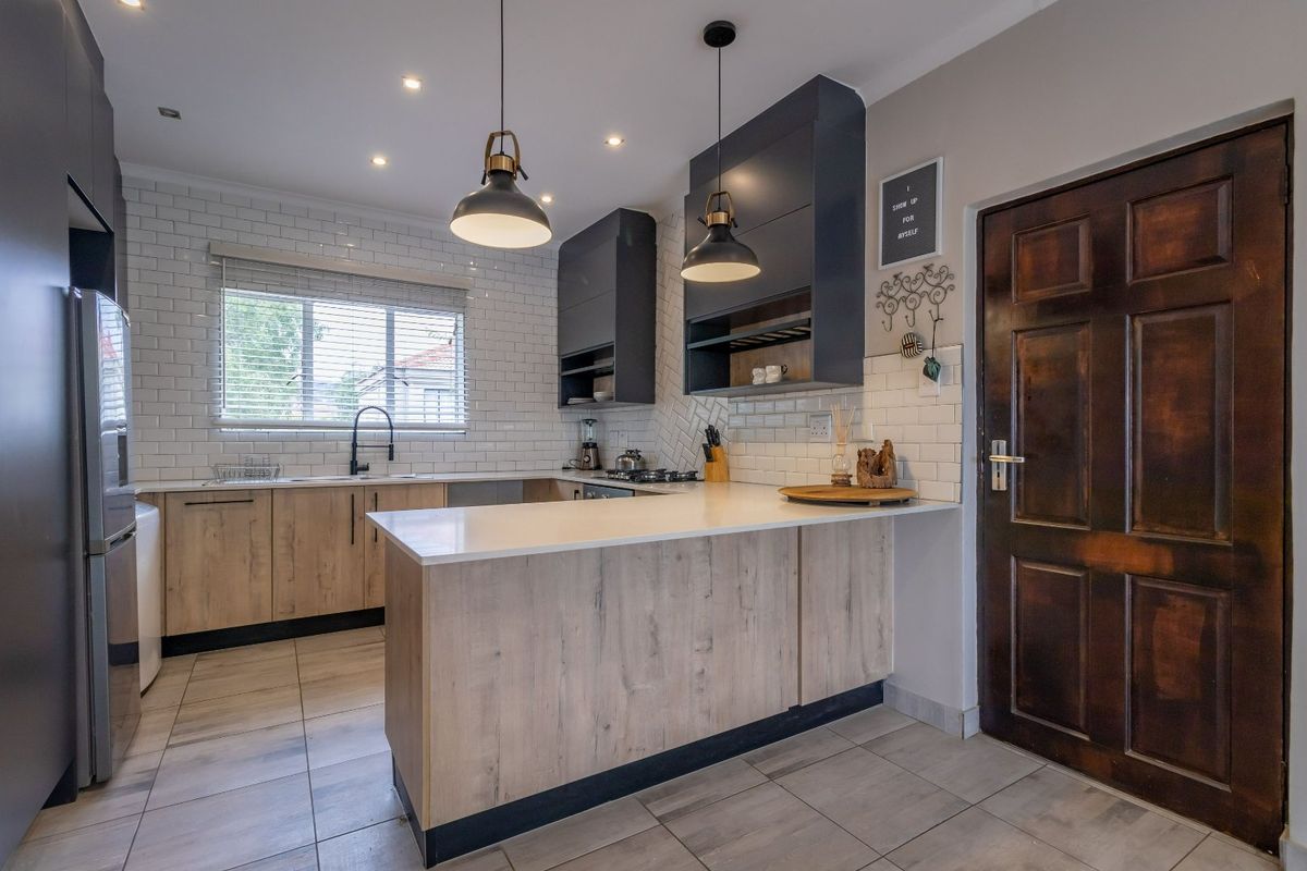 Modern kitchen featuring wood-look cabinetry, white quartz countertops, subway tile backsplash, and high-quality fixtures, offering a clean and functional culinary space.