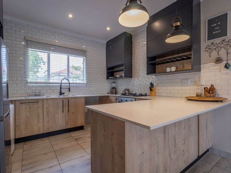 Modern kitchen featuring wood-look cabinetry, quartz countertops, a stylish herringbone subway tile backsplash, and high-quality integrated fixtures.
