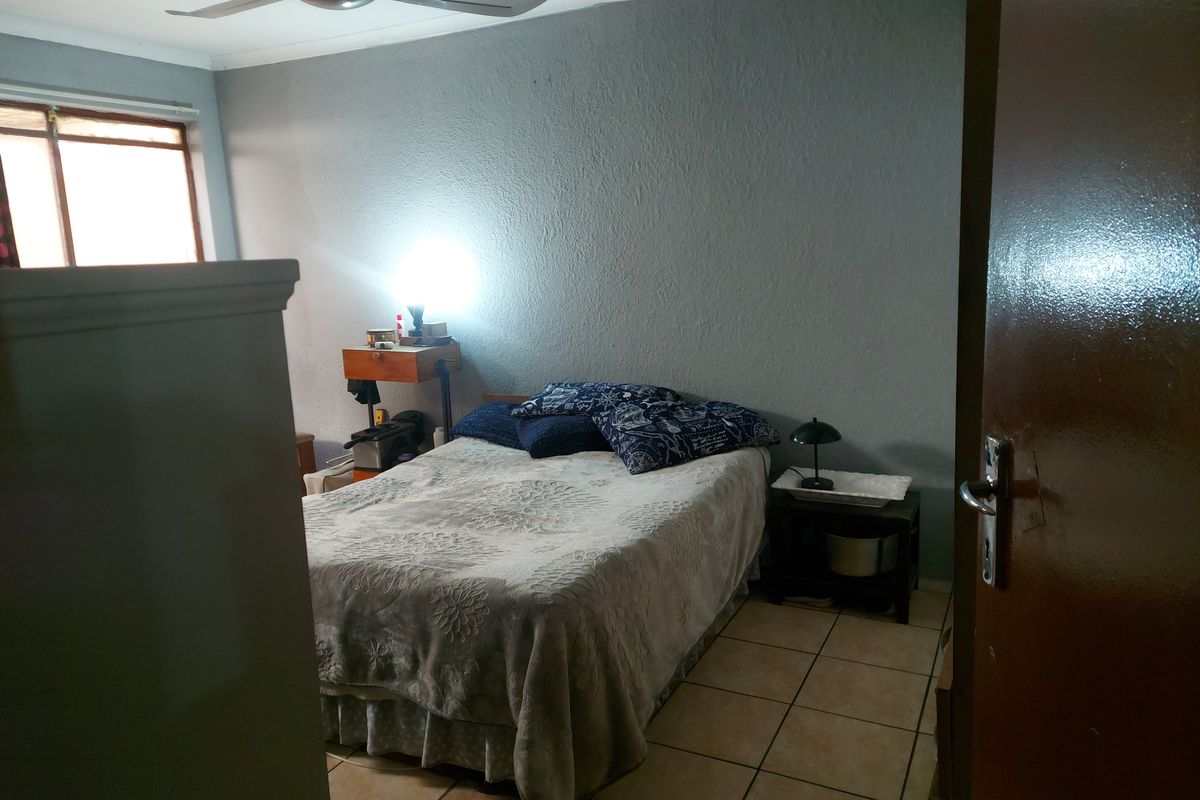 A bedroom featuring tiled flooring and a ceiling fan, requiring cosmetic updates to improve the overall aesthetic and condition of the space.
