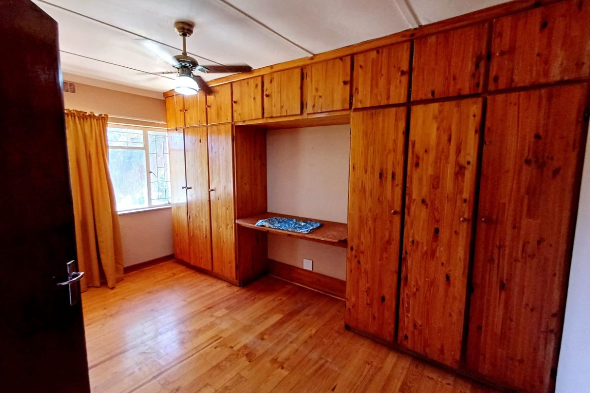 A bedroom featuring extensive built-in wooden cabinetry, a integrated desk, ceiling fan, and wooden flooring, offering a functional and classic layout.