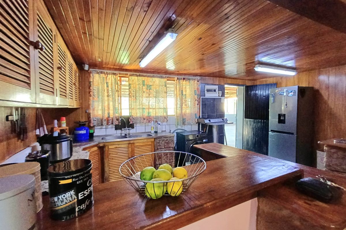 A rustic kitchen featuring extensive wooden cabinetry, a breakfast bar, and a timber-clad ceiling, offering a warm but dated aesthetic ready for modernization.