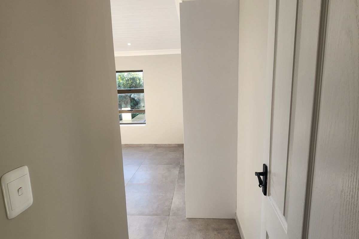 A bright, empty room featuring modern large-format floor tiles, a white tongue-and-groove ceiling, and a clean, neutral interior finish.