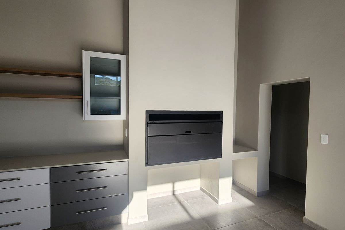 A modern living area featuring a built-in fireplace, sleek cabinetry with integrated storage, and large format floor tiles.