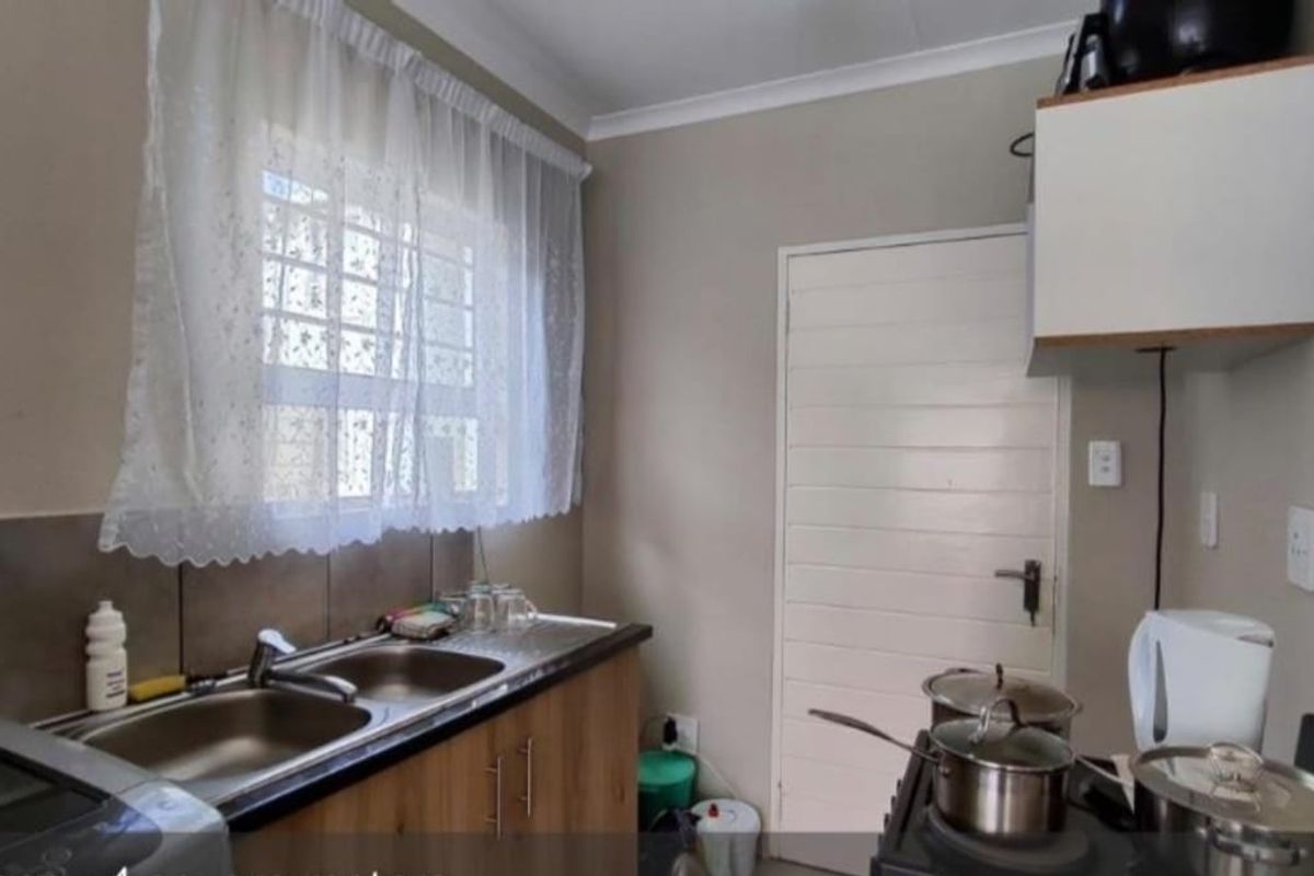 A functional kitchen featuring a double sink, tiled splashback, and built-in cabinetry, providing a practical workspace for daily culinary needs.