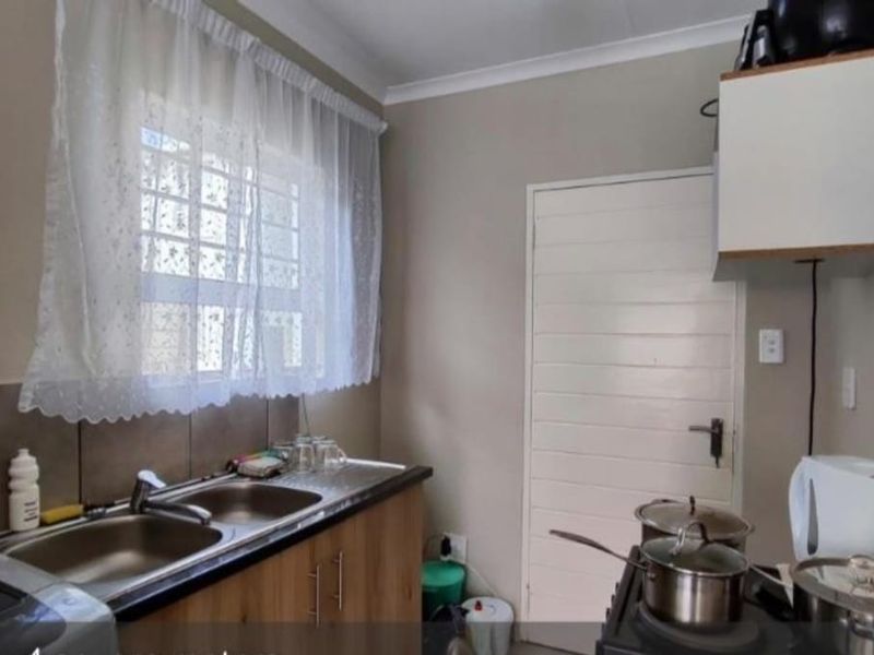 A functional kitchen featuring a double sink, tiled splashback, and built-in cabinetry, providing a practical workspace for daily culinary needs.