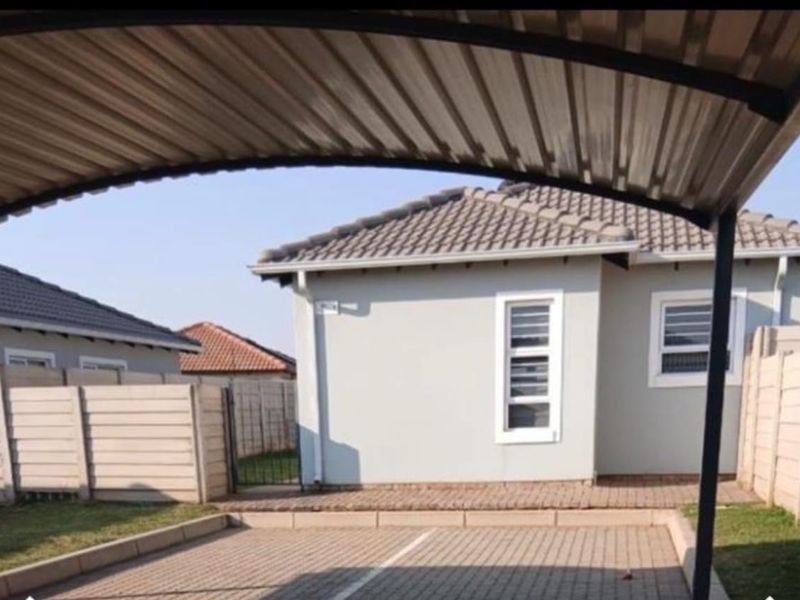 Exterior view of the property featuring a covered carport, paved driveway, and secure perimeter walling.