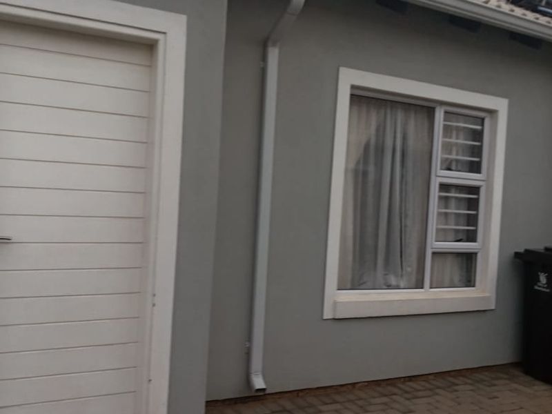 Exterior view of the property featuring a paved patio area, solar water heating system, and secure window fittings.