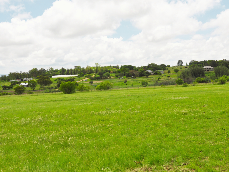 A wide-angle view of the expansive, open residential land featuring lush green grass and surrounding rural landscape.