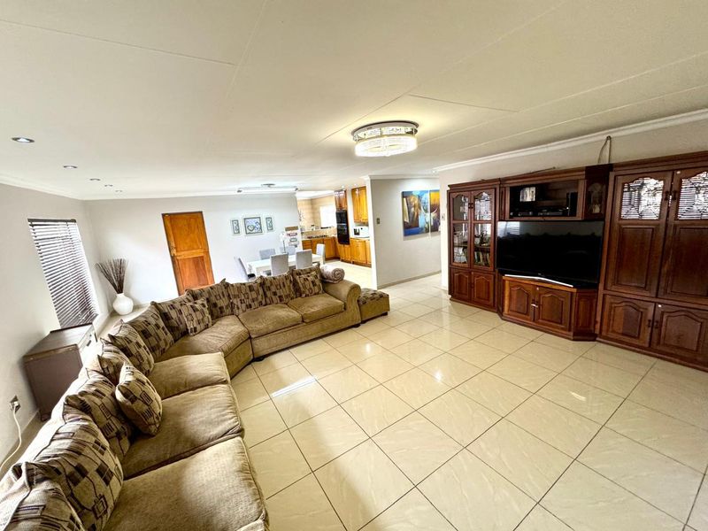 Spacious open-plan living area featuring tiled flooring, recessed lighting, and a seamless flow into the adjacent kitchen space.