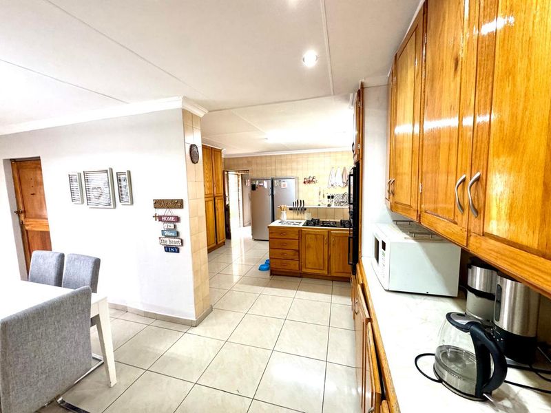 Open plan kitchen and dining area featuring wooden cabinetry, tiled flooring, and built-in cooking appliances.