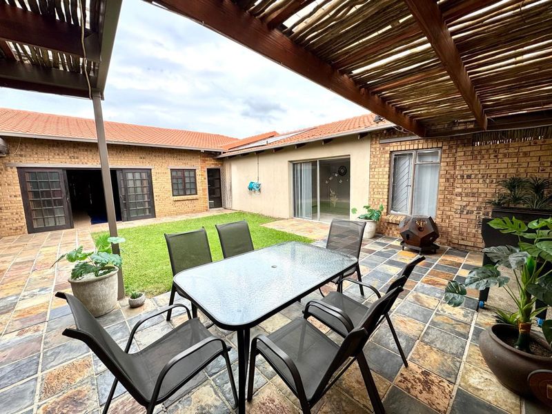 A covered outdoor patio area featuring slate tile flooring and a timber pergola, providing a seamless transition to the garden and interior living spaces.