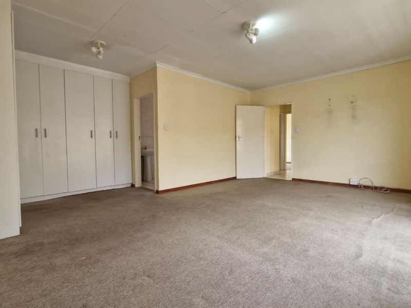 Spacious bedroom featuring built-in cupboards, carpeted flooring, and coved ceilings, offering a blank canvas ready for modernization and personal touches.
