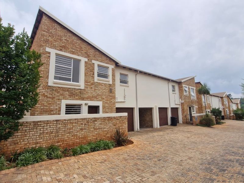A view of the townhouse complex exterior featuring face brick facades, paved driveway access, and integrated garage bays.