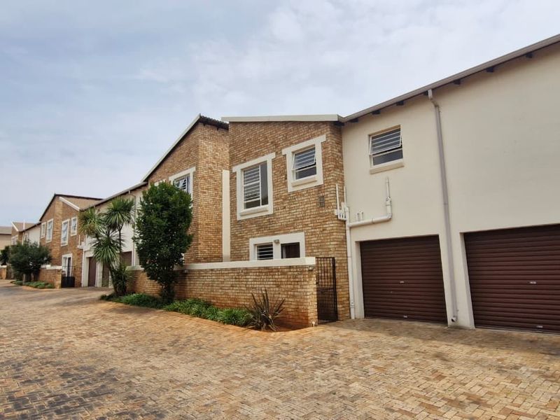 Exterior view of a townhouse complex featuring brick facades, paved driveway access, and integrated roller garage doors.