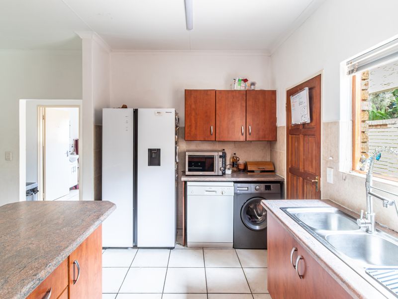 Functional kitchen featuring laminate countertops, double bowl sink, tiled flooring, and built-in cabinetry with integrated appliance space.