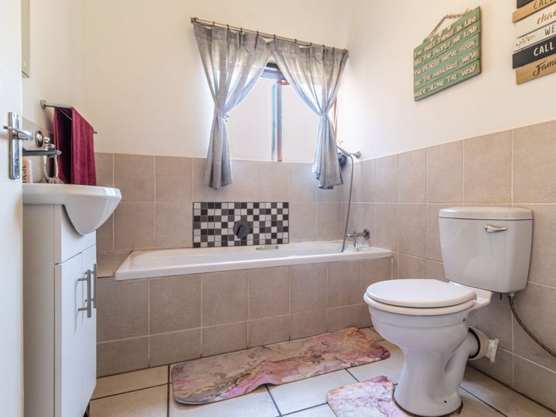 A functional bathroom featuring a bathtub with tiled surround, a standard toilet, and a vanity cabinet with a washbasin.