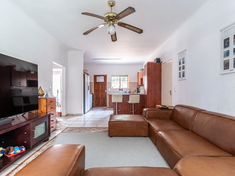 Open-plan living area featuring a kitchen with breakfast bar, tiled flooring, and a ceiling fan, creating a functional and connected living space.
