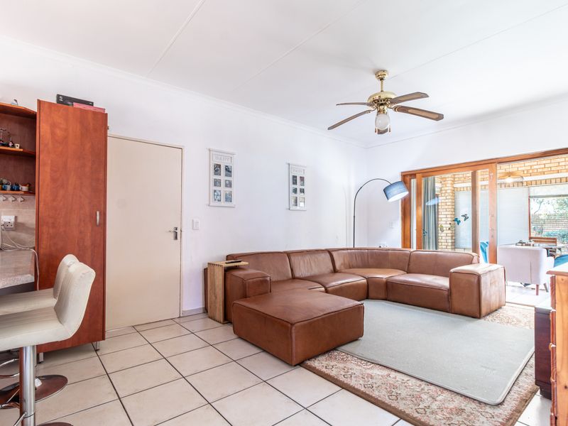 Spacious living room featuring tiled flooring, a ceiling fan, and large sliding glass doors that provide access to the outdoor patio area.